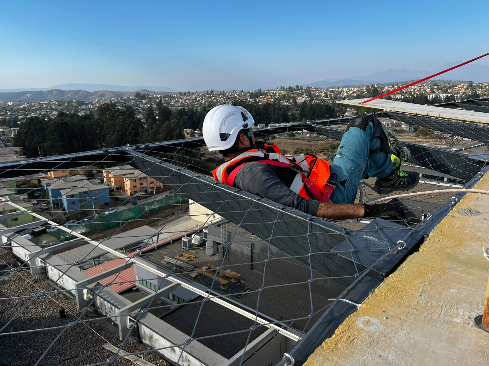 Técnico instalando una malla de protección en una techumbre